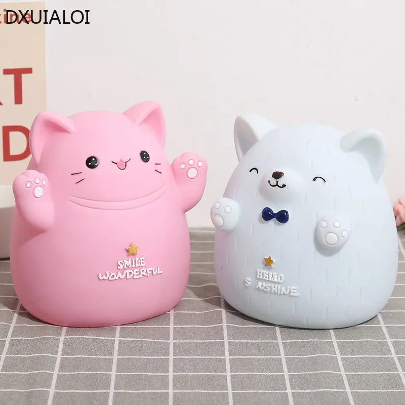 A pink cartoon cat figure with a smiling face and a white bear figure are displayed on a gray surface.