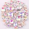 A mix of silver claw setting glass rhinestones in jelly candy AB colors scattered on a white background.