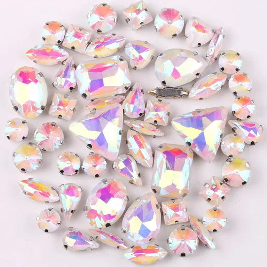 A mix of silver claw setting glass rhinestones in jelly candy AB colors scattered on a white background.