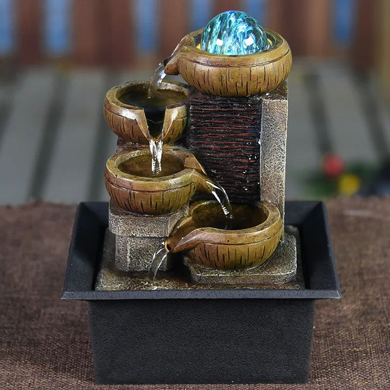 A tabletop water fountain featuring a glass orb, flowing water, and natural stone elements.