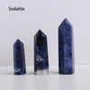 A vertical blue sodalite crystal point prism tower displayed on a white surface.