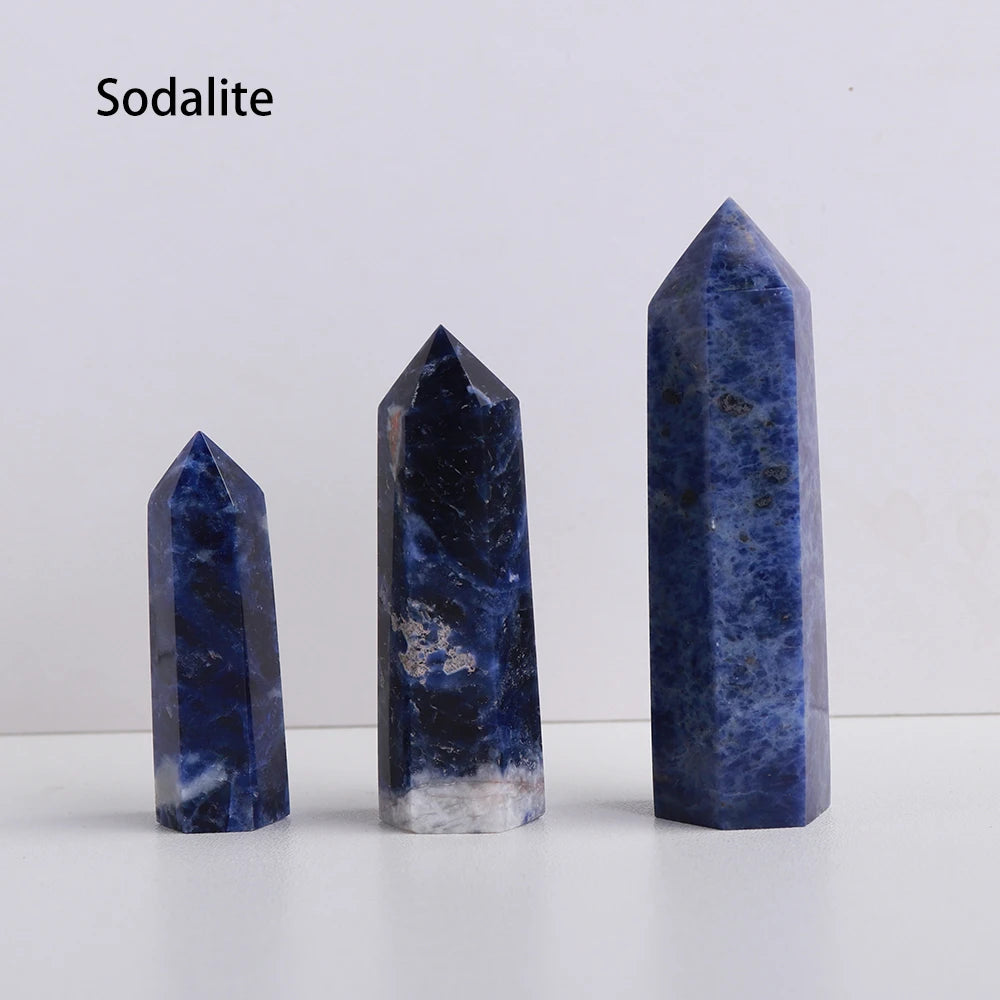 A vertical blue sodalite crystal point prism tower displayed on a white surface.