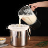 A hand pours white liquid from a fine mesh filter bag into a metal container.