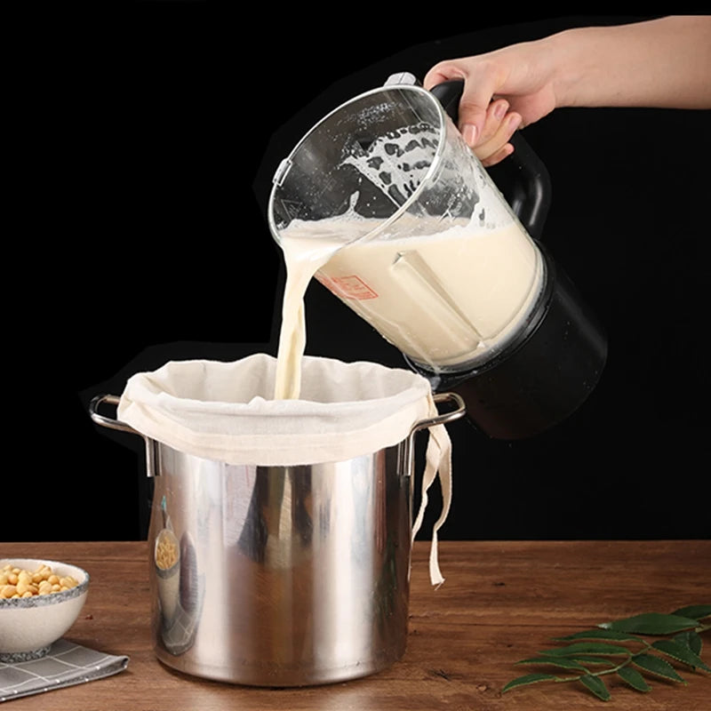 A hand pours white liquid from a fine mesh filter bag into a metal container.