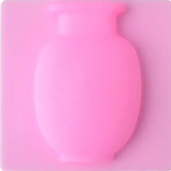 A pink flexible self-adhesive wall flower vase with a rounded body and narrow neck.
