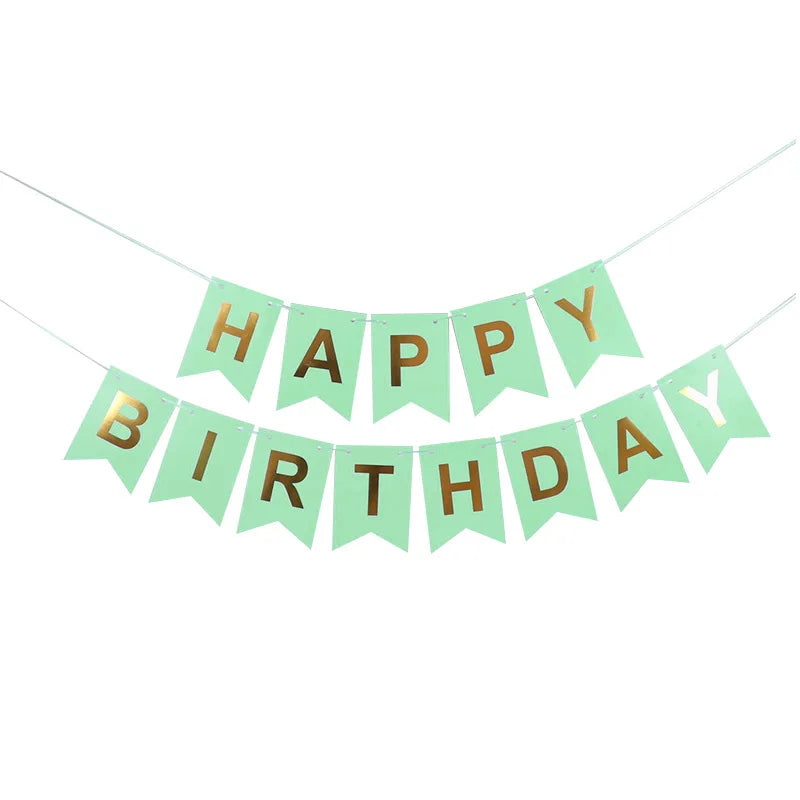 Decoración de bandera con la frase 'HAPPY BIRTHDAY' en letras doradas sobre un fondo verde claro.