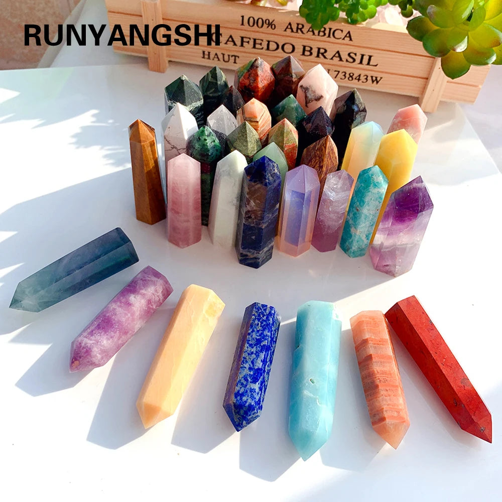 A collection of natural crystal point prisms in various colors and shapes arranged on a white surface.
