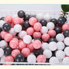 A white plastic basket filled with a 50-pack of colorful, round, glittery balls in shades of pink, white, and black.
