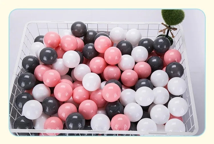 A white plastic basket filled with a 50-pack of colorful, round, glittery balls in shades of pink, white, and black.