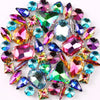 A mix of iridescent glass rhinestones in various colors including purple, green, pink, and blue set in silver claws.