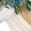Elegant chiffon fabric in white and beige tones draped with green leaves and pink and blue roses for a wedding arch.