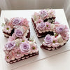 A set of purple and pink floral cake toppers featuring gold butterfly accents on dark chocolate cakes.