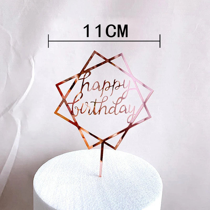 Rose gold acrylic happy birthday cake topper with a geometric design on a white cake.