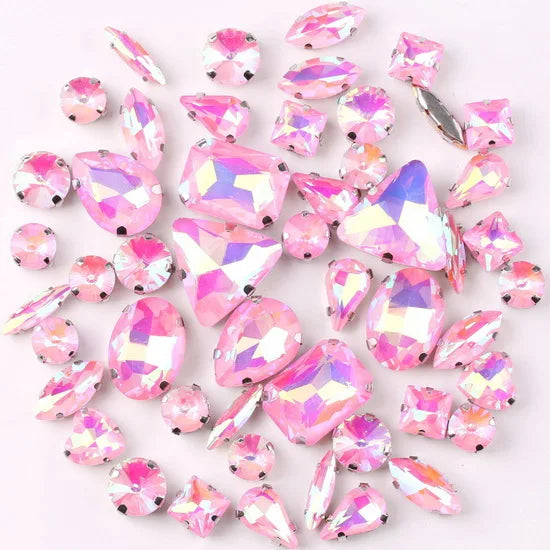 A mix of silver claw setting glass rhinestones in jelly candy AB colors scattered on a white background.
