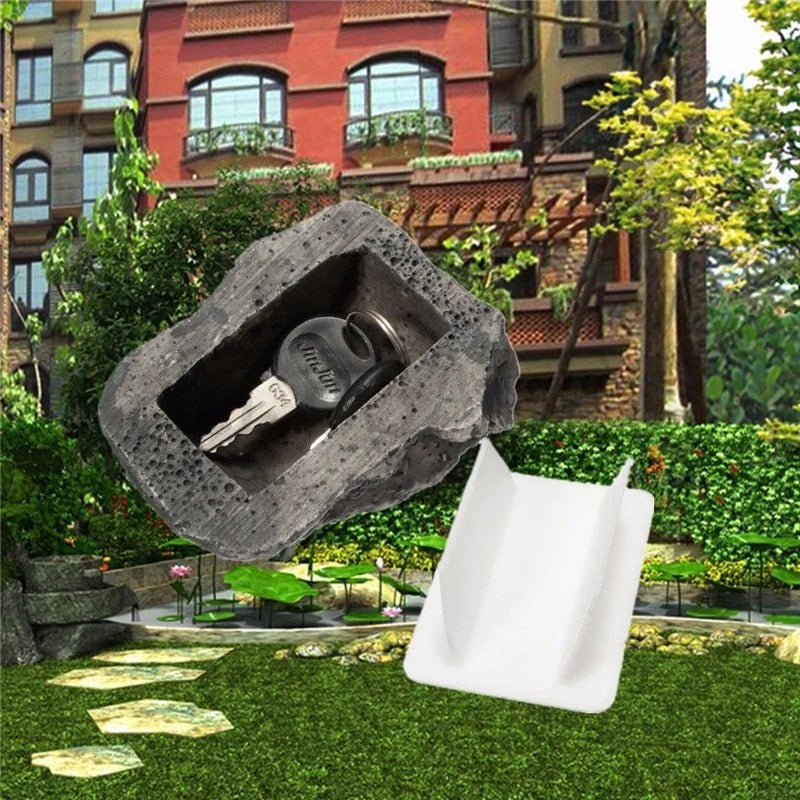 A decorative garden key is hidden inside a large, rough stone, placed on green grass.