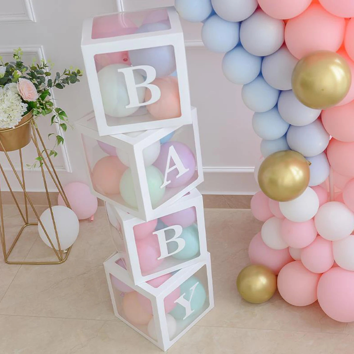 A display of pink, blue, and gold letter balloons arranged in a vertical box structure for baby shower decorations.