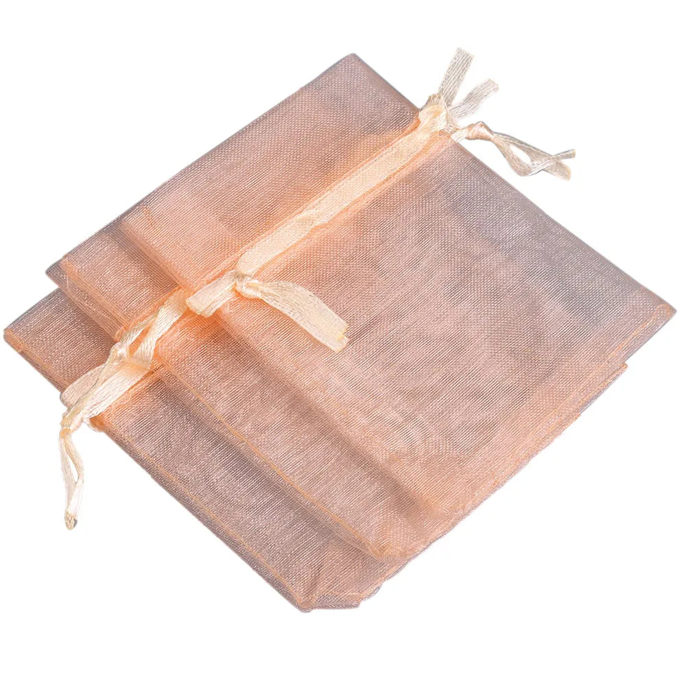 A stack of light peach organza drawstring gift pouches tied with thin twine.