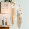 Boho macrame dream catcher wall decor featuring white and gold fringe hanging on a white wall.