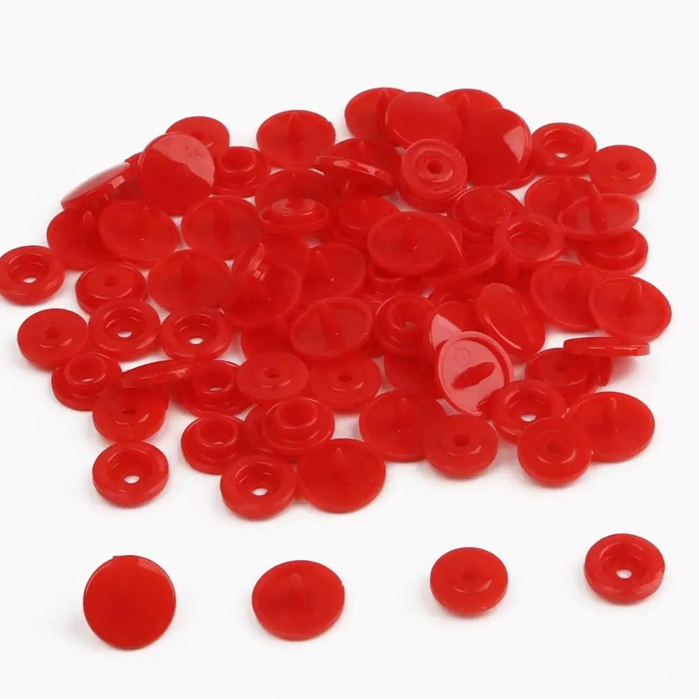 A pile of assorted red snap buttons in various sizes for crafting.