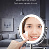 A hand is touching the sensor of a round LED makeup mirror used for dimming light.