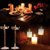 Elegant glass candle holders with lit candles arranged on a dark wooden table setting.
