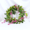 A green silk wisteria garland vine with pink flowers used for weddings and home decor.