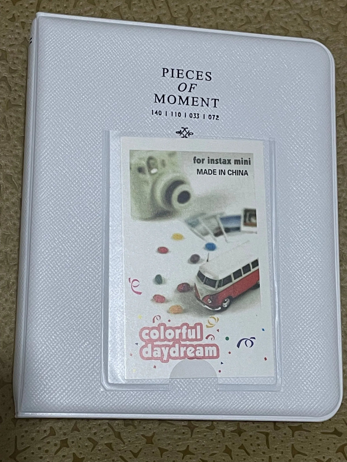 A clear plastic photo album titled Pieces of Moment for Instax mini made in China featuring colorful daydream themes.