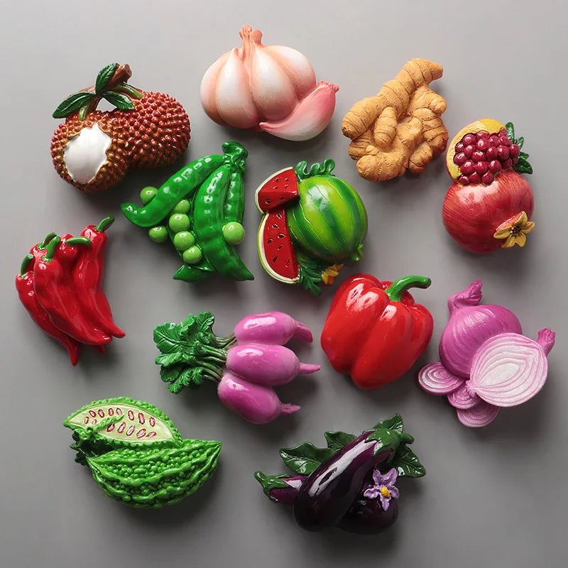A collection of realistic, colorful fruit and vegetable fridge magnets including a pumpkin, corn, peppers, onions, and variou
