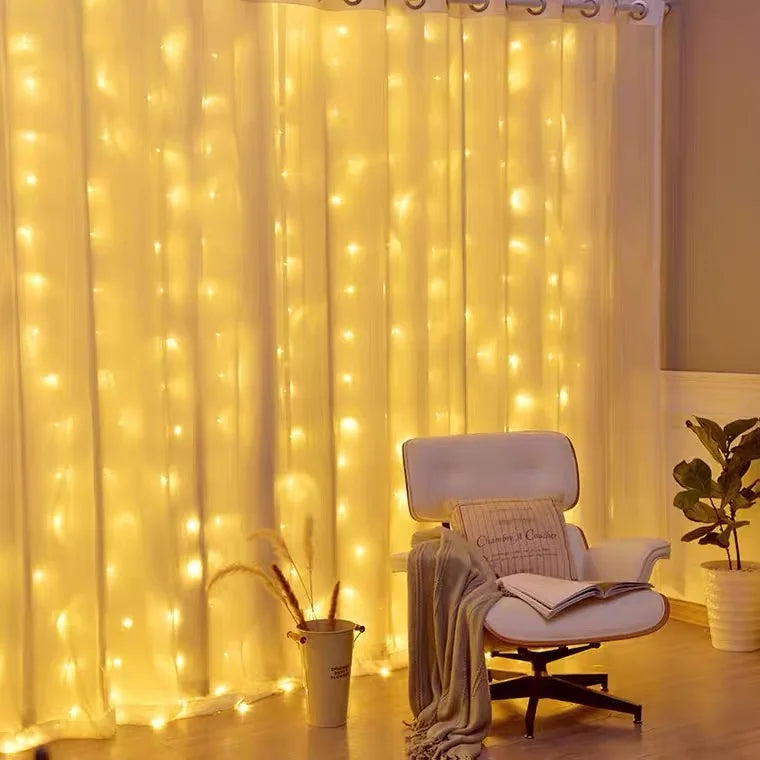 Warm white LED curtain lights illuminating a window with a white chair and potted plant for Christmas décor