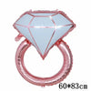 Globo de foil rosa en forma de diamante con diseño de corazón y un globo de anillo rosa.