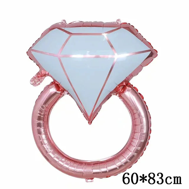 Globo de foil rosa en forma de diamante con diseño de corazón y un globo de anillo rosa.