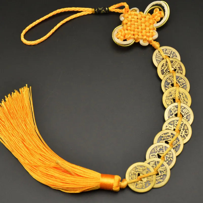 A necklace featuring an I Ching copper coin charm with a handwoven knot and orange thread.