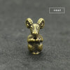 A small brass statue of a goat with horns, sitting on a dark gray surface.