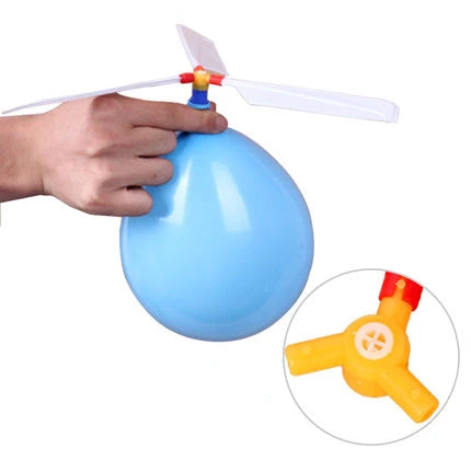A hand holds a blue balloon helicopter toy with a propeller attached.