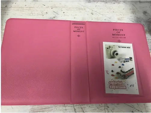 A pink photo album titled Pieces of Moment with a section showing an Instax mini camera.