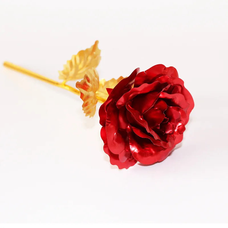 A deep red artificial rose with gold foil leaves on a white background.