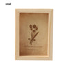 A small wooden photo frame with a light brown background featuring a delicate floral design and text.