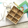 A wooden box filled with natural wooden clips for crafts, photos, and decor, resting on a white surface.