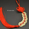 A red silk thread charm featuring six copper coins tied together with a handwoven knot.
