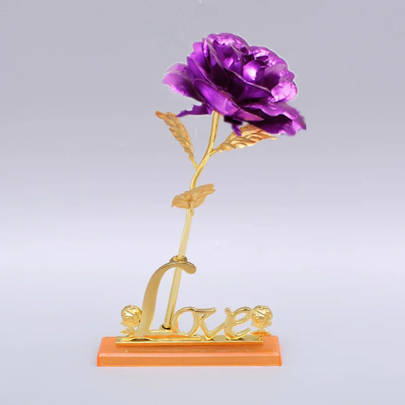 A gold foil artificial rose with a delicate stem and the word love on a small base.