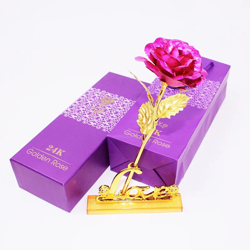 A purple box containing a gold foil artificial rose and a gold-colored stand.