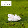 A white miniature rabbit figurine lying on green grass.
