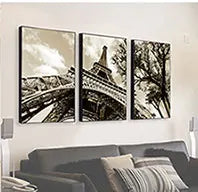 Three framed black and white photographs of a bridge and trees displayed on a white wall.