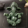 Handcrafted green Buddha statue with a serene expression sitting in a meditative pose.