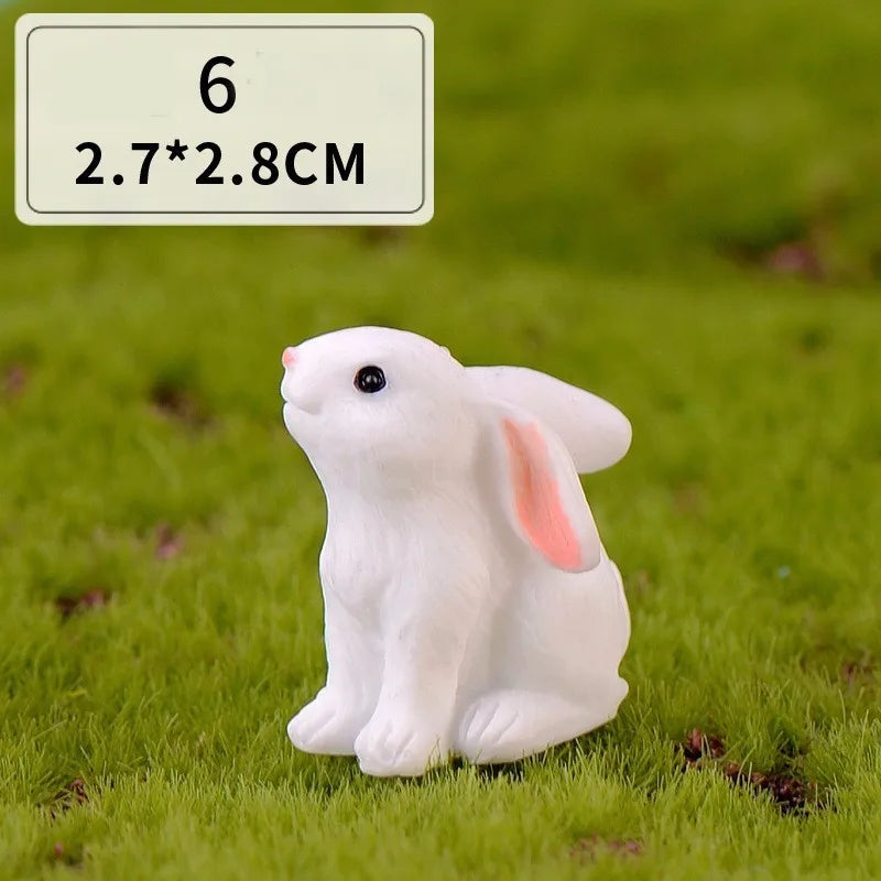A white miniature rabbit figurine sitting on green grass.