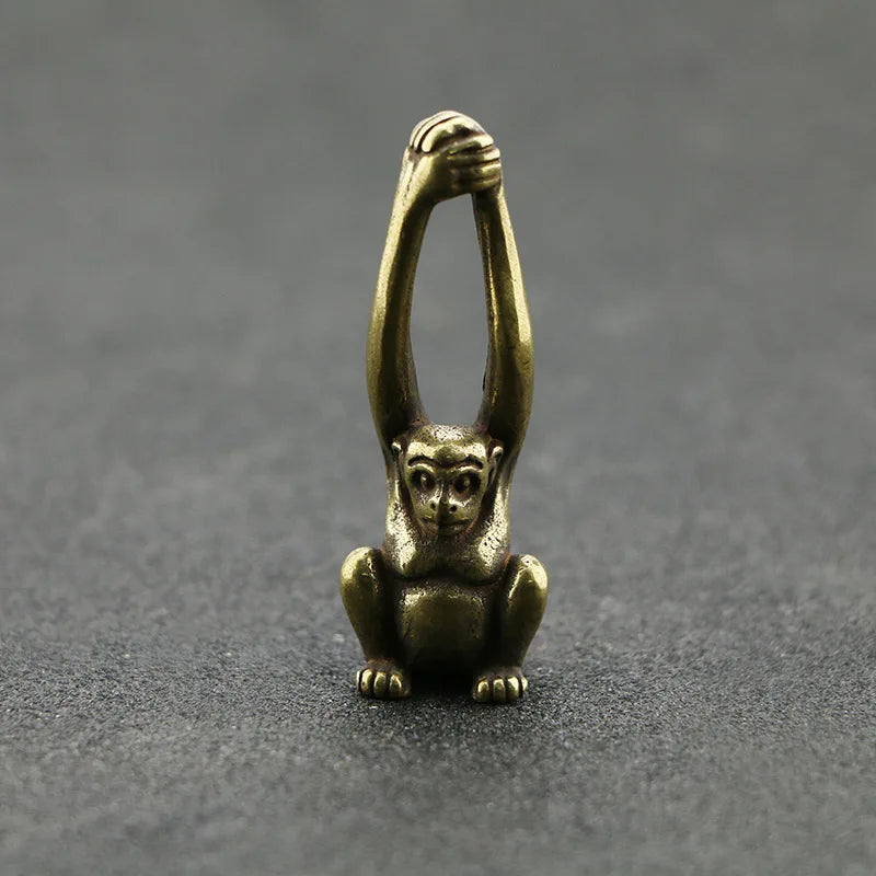 Vintage brass monkey key chain charm with a grasping hand design