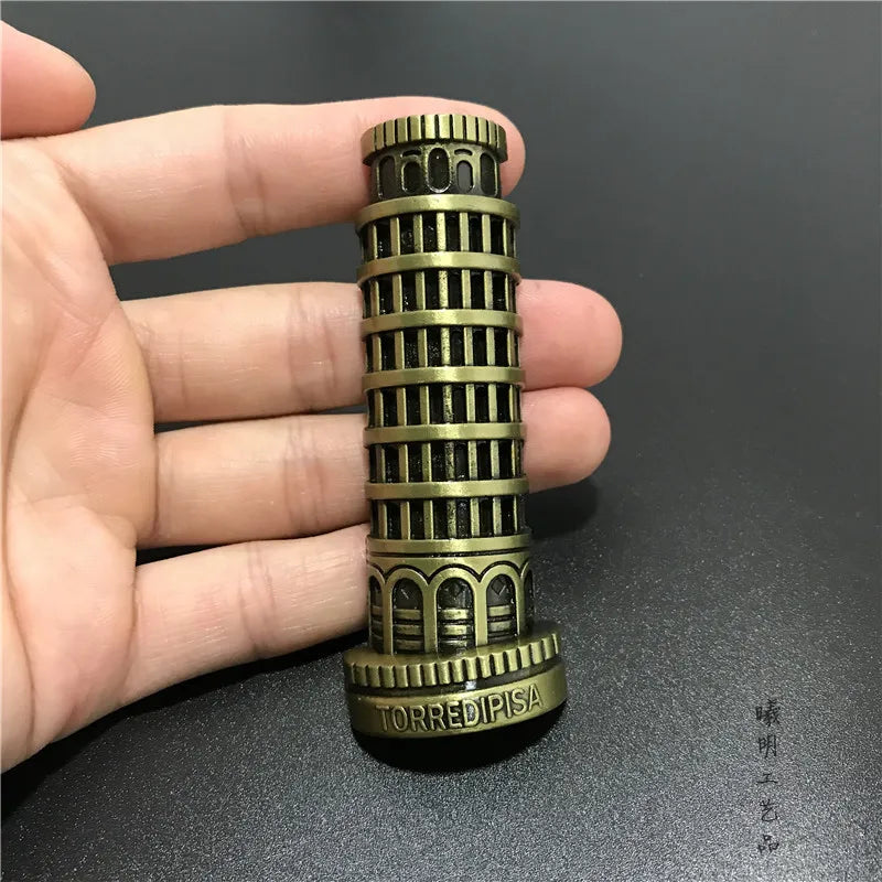 Une main tient un aimant réfrigérateur décoratif en métal, en forme de colonne ou de tour antique.