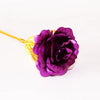 A deep purple artificial rose with a gold foil stem and leaves.