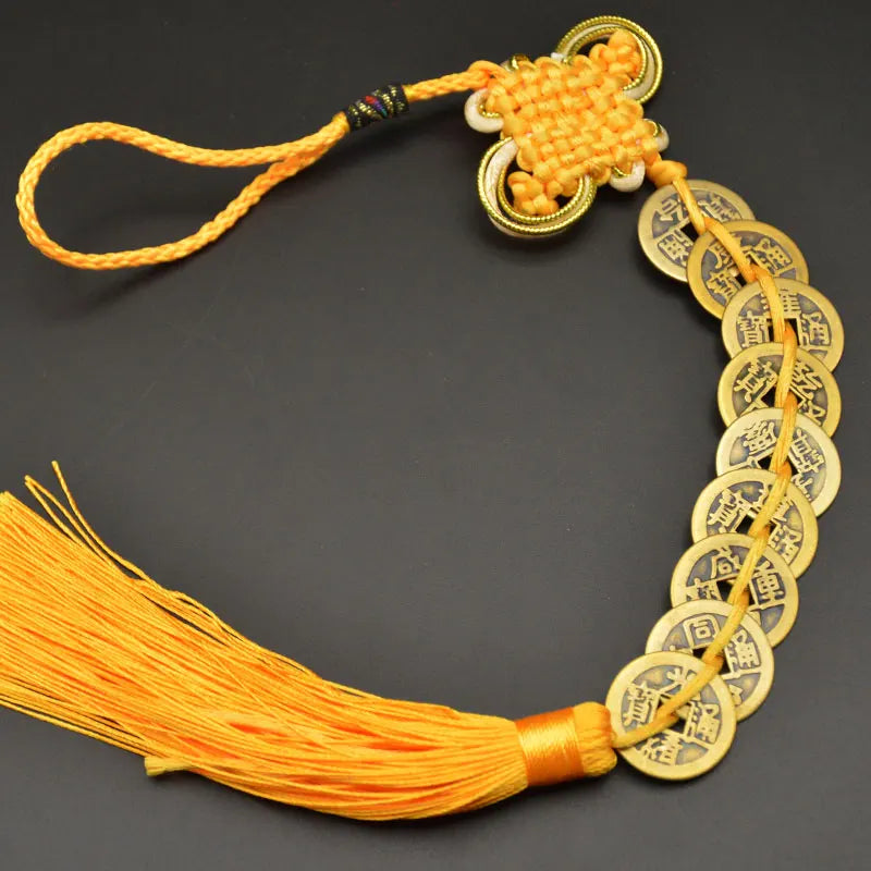 A handwoven knot charm featuring copper coins and a yellow silk tassel for Feng Shui.