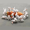 A collection of white miniature rabbit figurines sitting on an orange pumpkin.